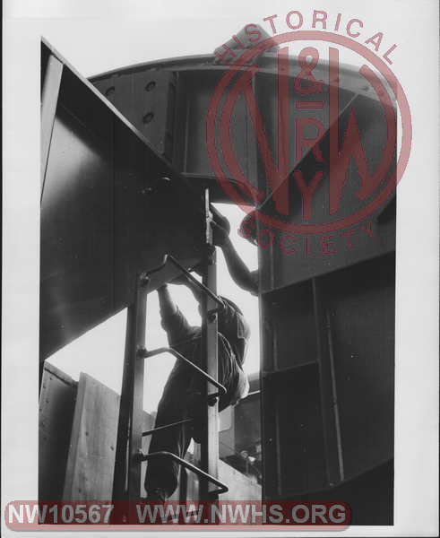 Closeup view of men measuring clearance between Class H-13 Hopper 93000 at entrance to of rotary dumper on one of the Lambert's Point Coal Piers